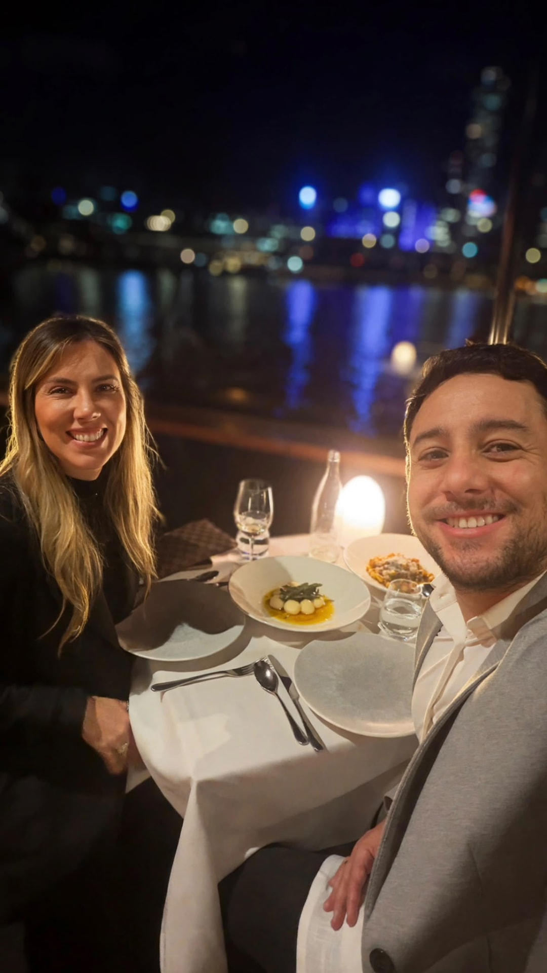 Alvaro e Priscila em um jantar à beira d'água à noite