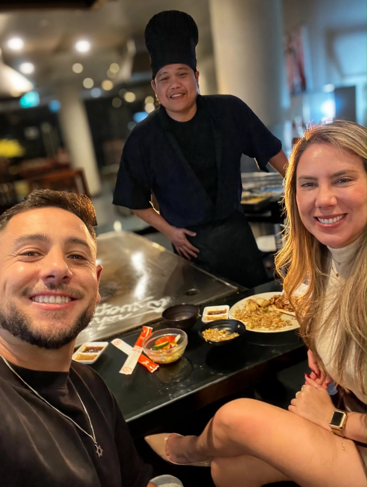 Alvaro e Priscila em um jantar de teppanyaki, com o chef ao fundo