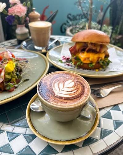 Café com latte art, hambúrguer e salada em uma mesa de café em Brisbane