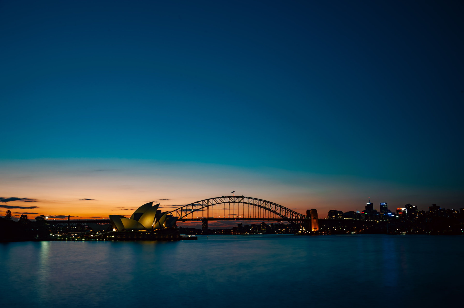 Sydney ao anoitecer: a Opera House e o Harbour Bridge iluminados