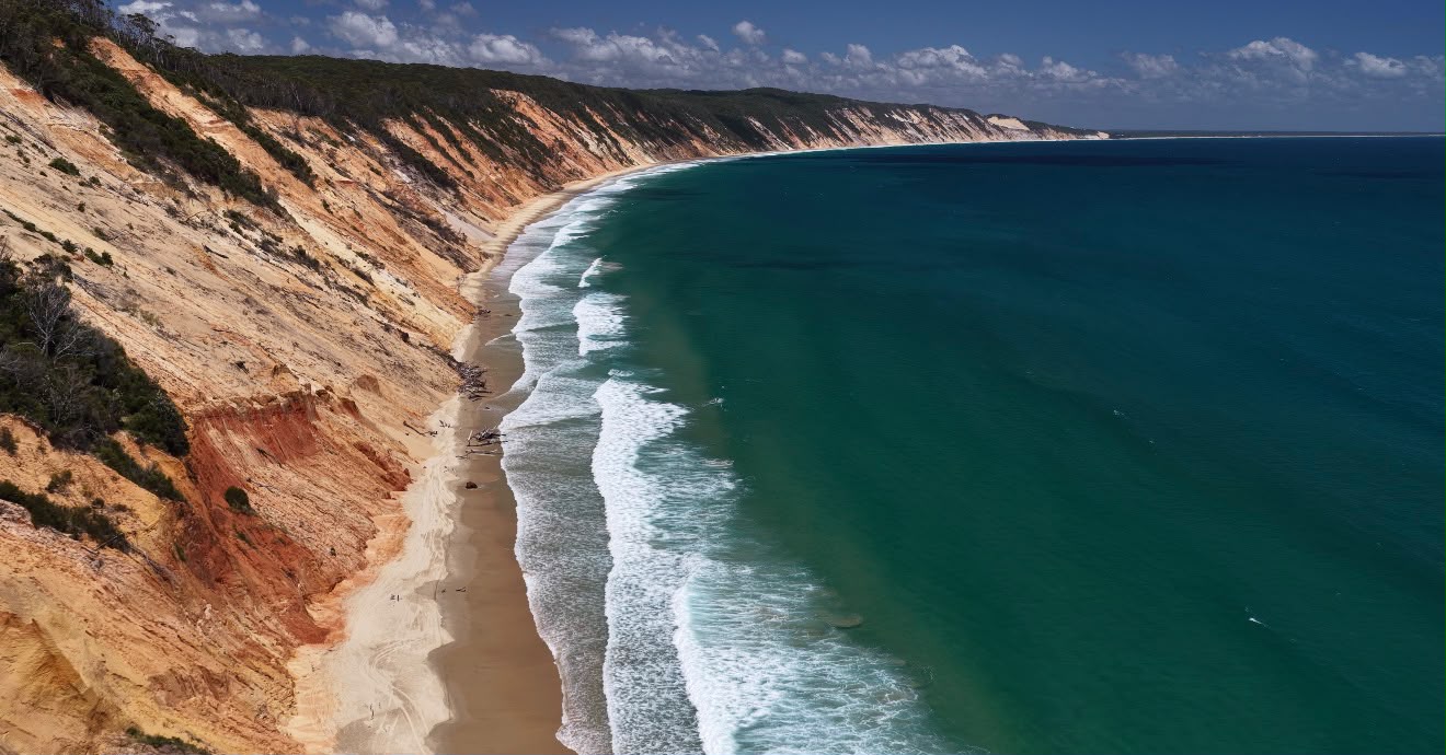 Vista aérea de falésias coloridas, praia e mar azul-turquesa