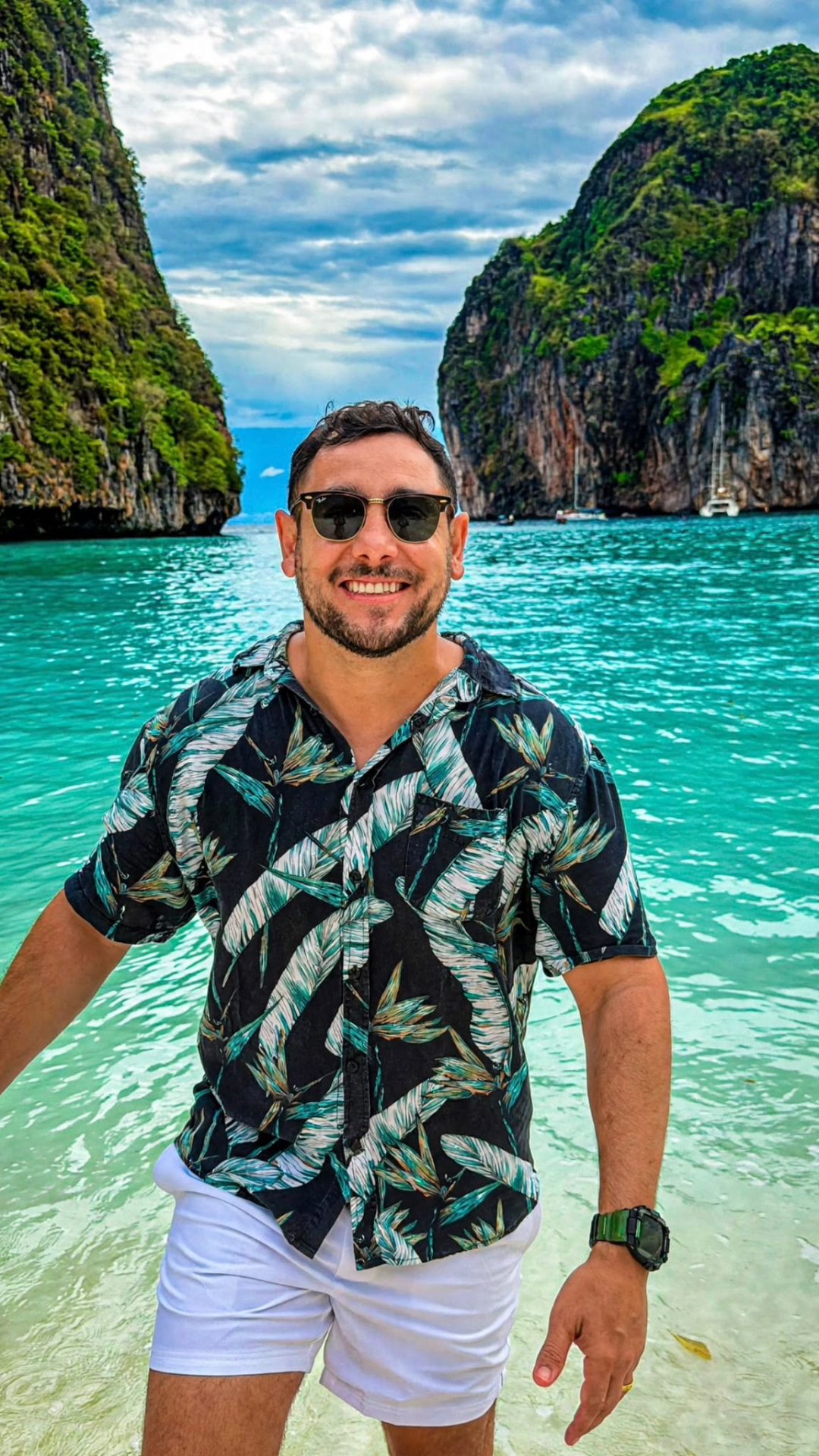 Alvaro em pé na água rasa de uma enseada, com falésias ao fundo