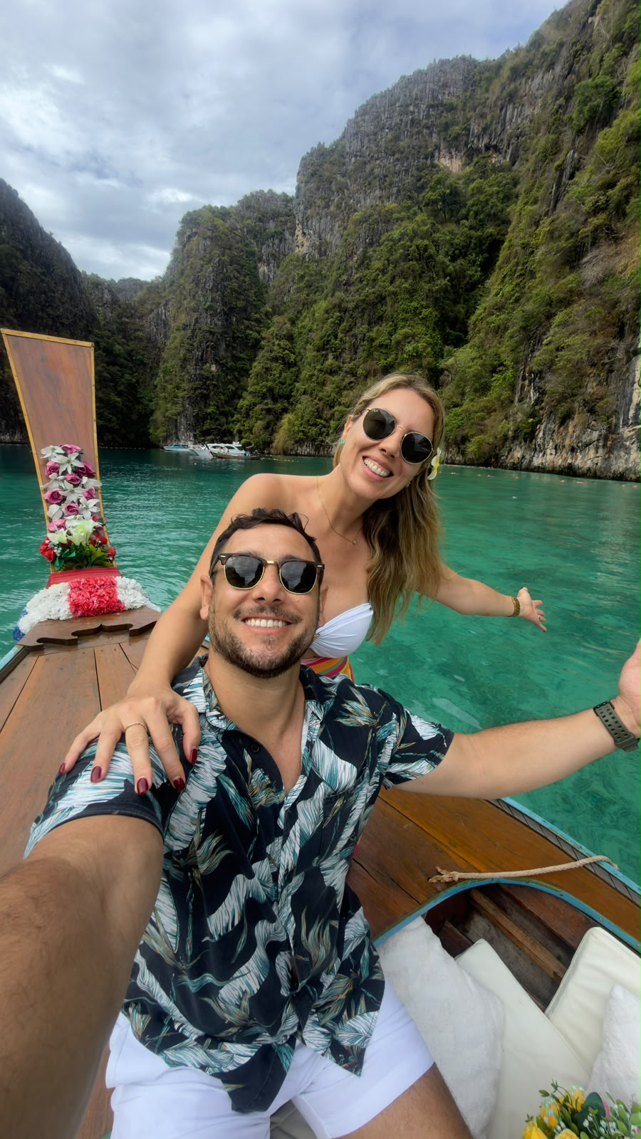 Nós em um barco de cauda longa em águas turquesa entre falésias